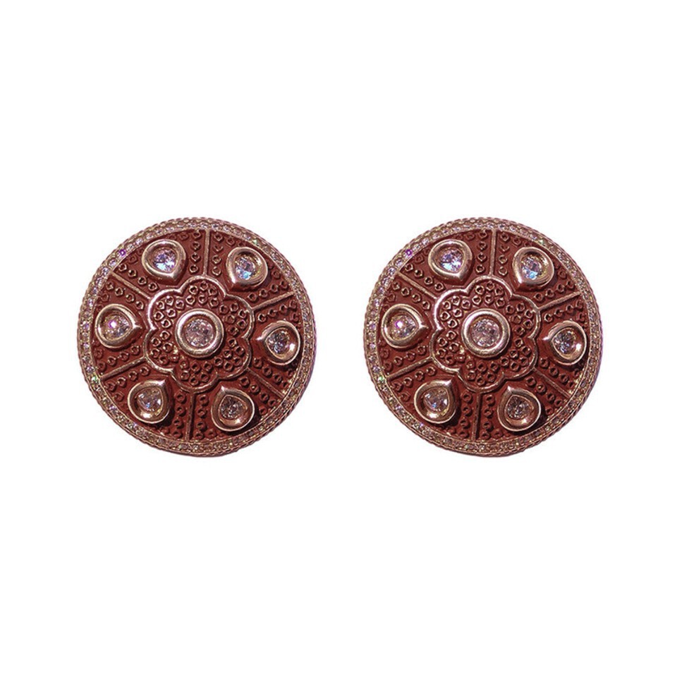 Round copper-toned stud earrings with embossed floral design and clear stones