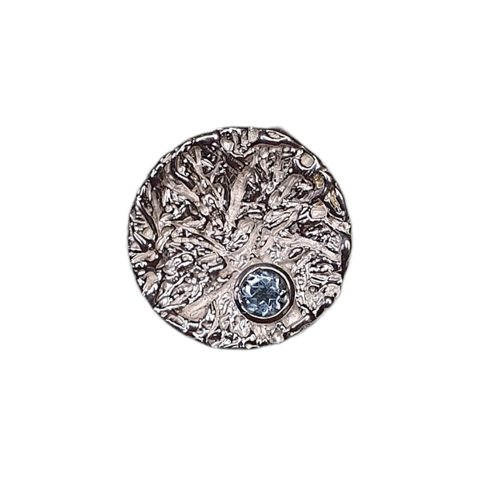 Textured round silver pendant with blue gemstone accent
