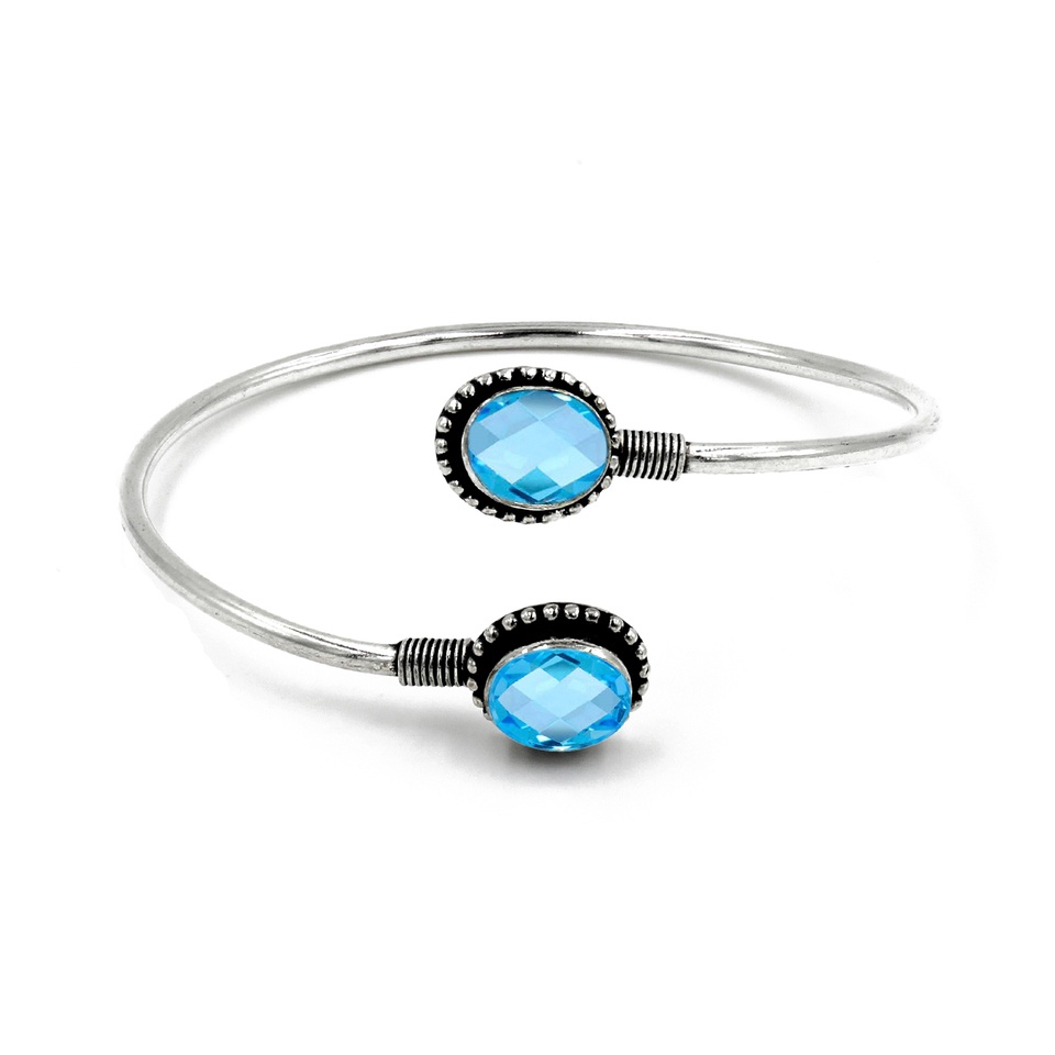 Silver cuff bracelet with dual oval faceted blue topaz gemstones